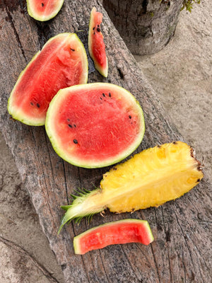 Sliced watermelon and pineapple on a wooden surface