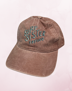 Pink hat with 'Surf Sister Tofino' text on a light pink background