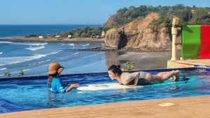 Two people in a pool with ocean and cliffs in the background