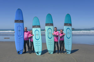 Four people holding surfboards on the beach 
