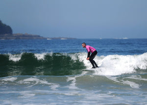 Person surfing on a wave in the ocean with a clear sky