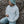 A lady sitting outdoors against a rocky surface wearing a light gray hoodie with 'SURF SISTER' logo on the chest. 